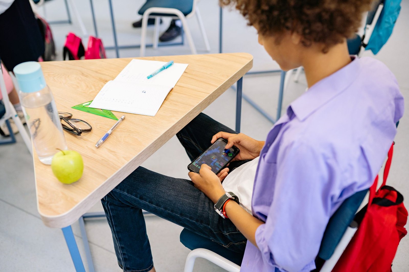 Student storing a phone in a backpack before the school day begins