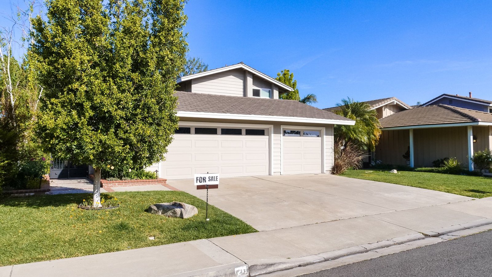 Suburban neighborhood street with for sale sign and houses