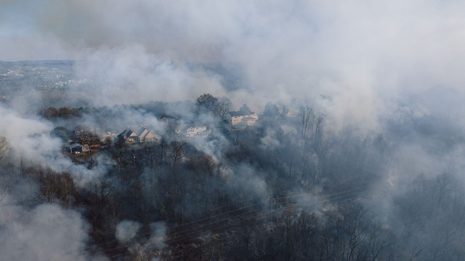 Smoke rising over a dry suburban neighborhood during wildfire season