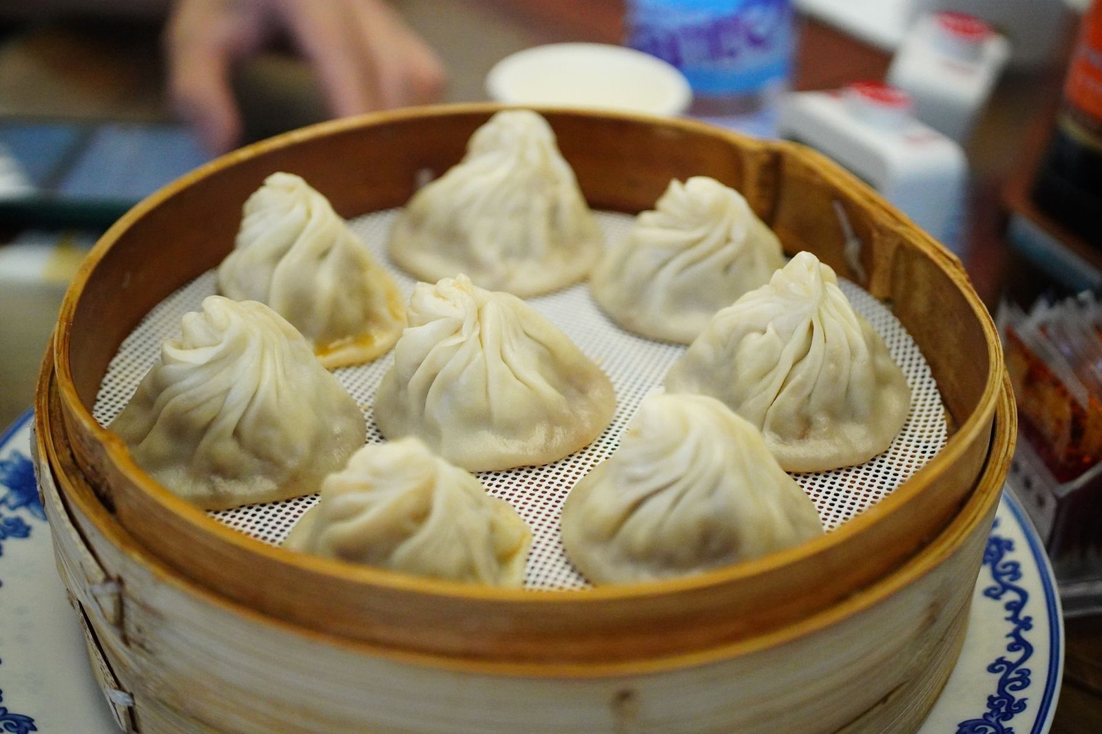 Soup dumplings in a bamboo steamer, representing Dumpling Queen's xiao long bao