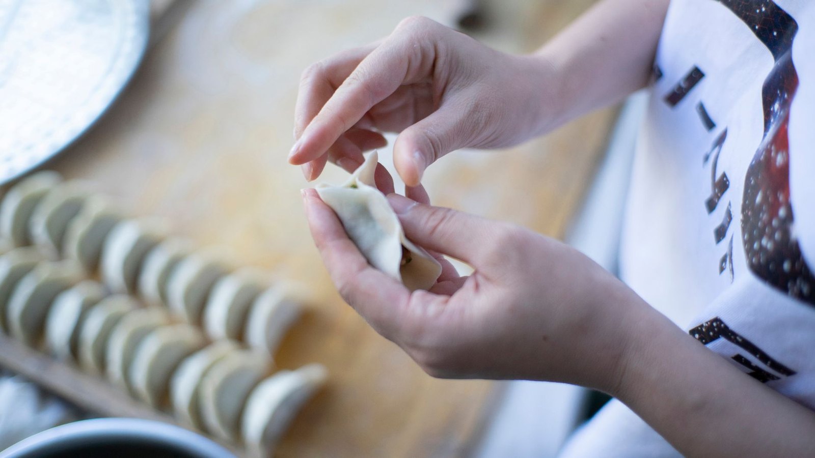 Chef folding handmade dumplings at a restaurant prep counter