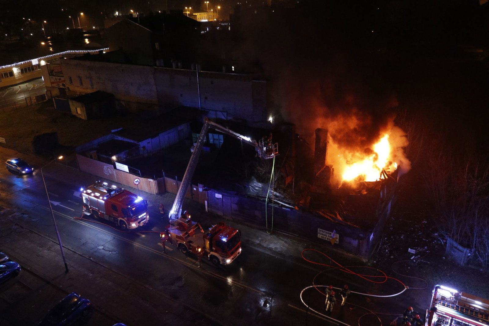 Fire trucks with extended ladders responding to a nighttime roof fire at a school building