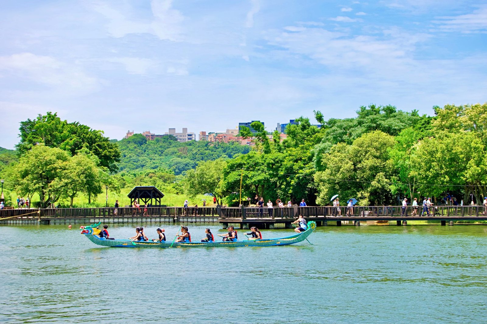 Colorful dragon boats with paddlers racing across a lake, drummer at the front