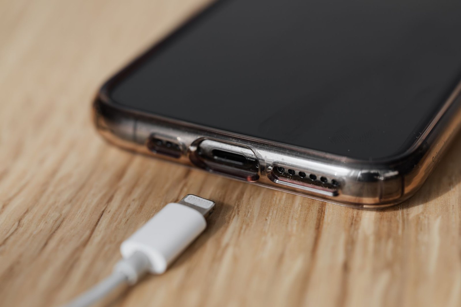 Smartphone charging on wooden desk surface