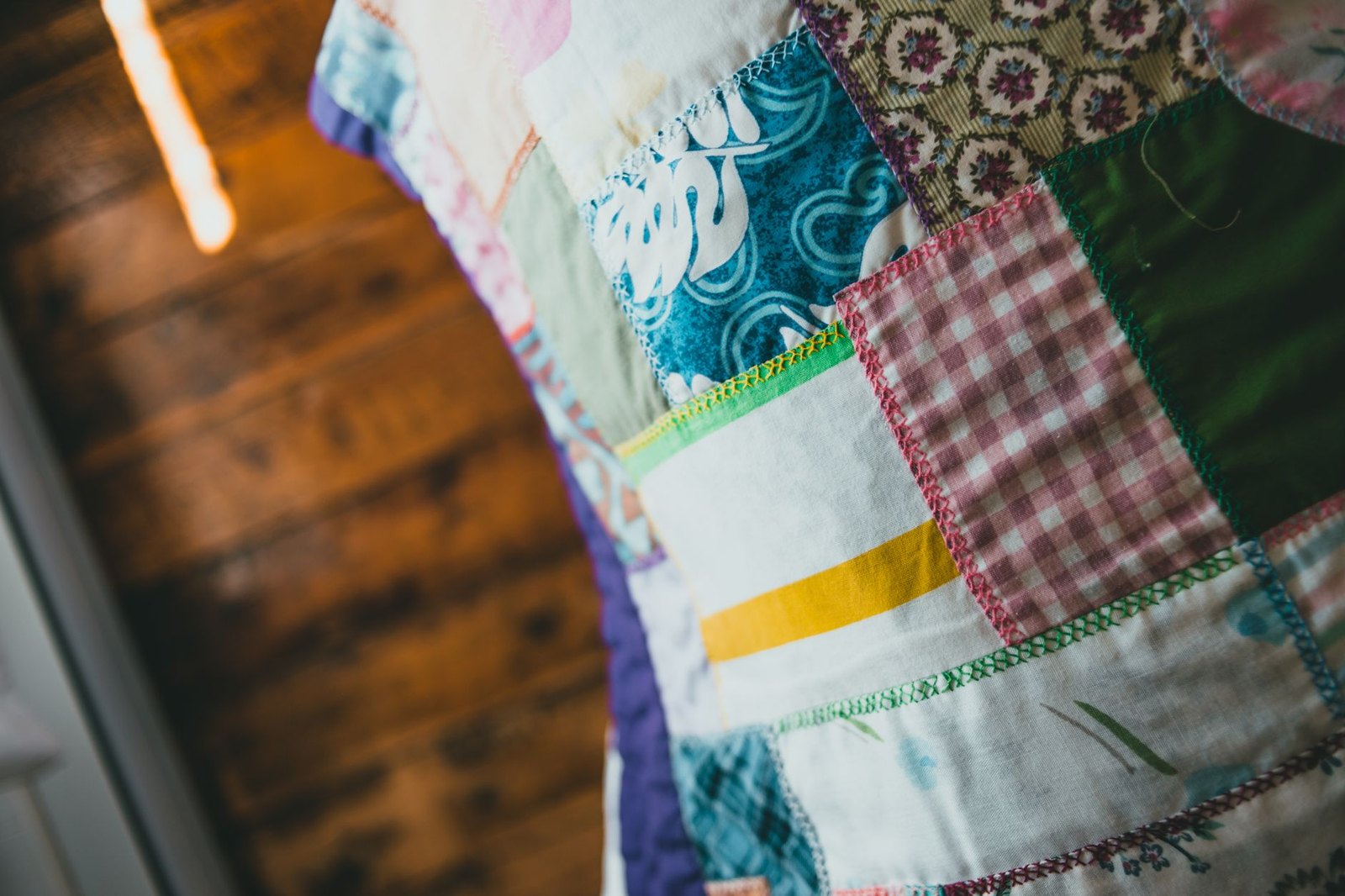 Colorful handmade patchwork quilts displayed on a wall inside a public library