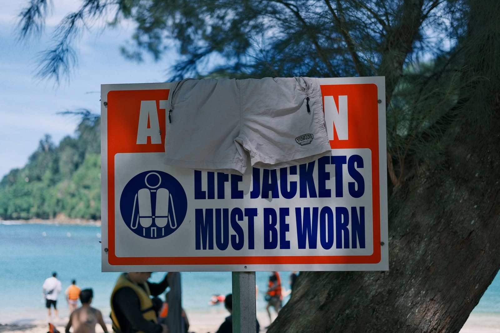 Water safety warning sign posted near a lake swim area requiring life jackets
